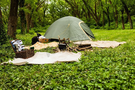 野餐的一天，在森林中的一个户外露营地，有游客绿色的露营帐篷和炉火上的锅。休闲和户外旅游概念