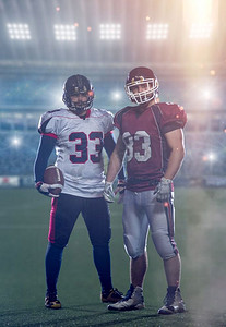 两名美式橄榄球运动员手持照明弹和灯光站在现代大型体育场的球场上