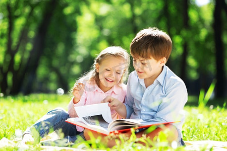 哥哥和妹妹在公园里看书。夏季周末户外活动