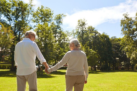 老年、退休和人的概念幸福的老年夫妇牵着手在夏季公园散步。快乐的高年级夫妇在夏季公园散步