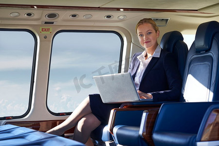 女商人在直升机机舱内用笔记本电脑工作的肖像