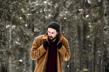 冬天森林里的人很冷，穿着棕色的外套，戴着手套