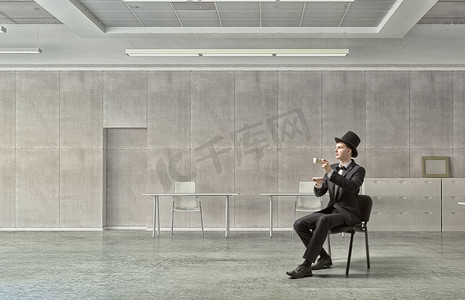 气瓶里的商人喝着咖啡。一位商人在办公室休息，喝着一杯热腾腾的芳香咖啡
