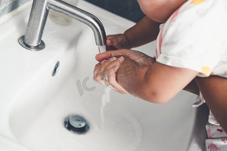 母亲洗手以预防新型冠状病毒病2019或COVID—19。人们在洗手池洗手以清除病毒感染。