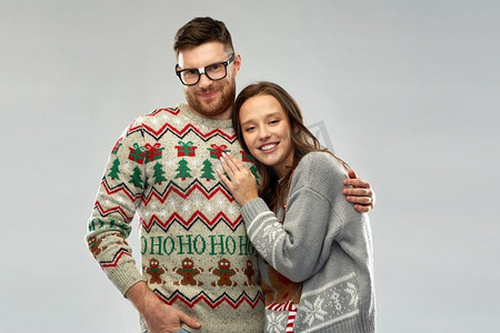 情侣衫摄影照片_圣诞节，人和节日的概念-丑陋毛衣派对上幸福的情侣肖像。圣诞丑陋毛衣派对上的幸福情侣