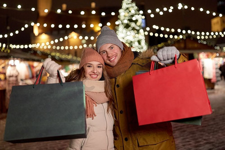 节日、圣诞节和人们概念快乐的情侣在冬天提着购物袋。冬天提着购物袋的幸福夫妻