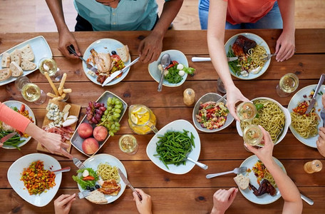 吃喝玩乐摄影照片_吃喝玩乐的概念--一群人在餐桌上与食物一起用餐。一群人带着食物在餐桌上吃饭