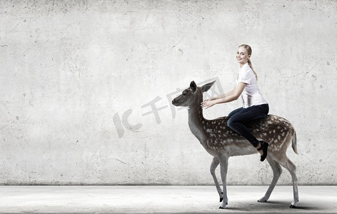 年轻漂亮无畏的女人骑着鹿的动物。女骑鹿