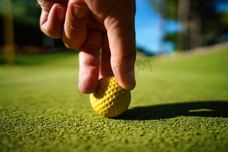 日落时分，绿色草地上的迷你高尔夫黄球