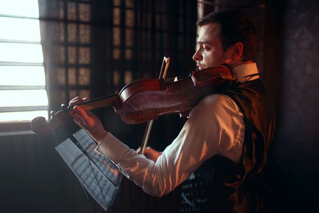 男提琴手用小提琴演奏古典音乐的肖像。有乐器的小提琴手。男提琴手拉着小提琴演奏古典音乐