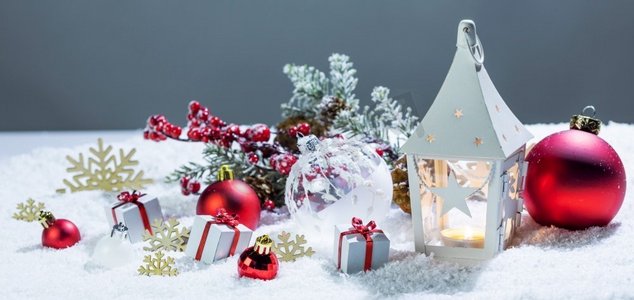 圣诞节假期卡与礼物，球，和白色发光灯笼在雪。圣诞装饰在雪