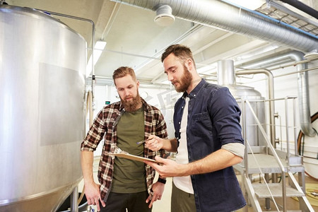 生产、商业和人的概念-在啤酒厂或非酒精啤酒厂拿着剪贴板的人。在啤酒厂或啤酒厂拿着剪贴板的男人