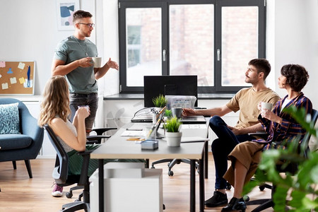 商业、人员和企业概念——由创业者或UI设计师组成的团队在办公室喝咖啡。团队的创业者喝咖啡在办公室