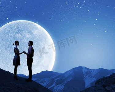 夜色摄影照片_浪漫的情侣。站在月光下的年轻浪漫情侣的剪影