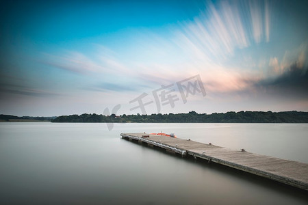 夏末时分，停泊在湖中码头上的休闲小船在日落时的美丽风景