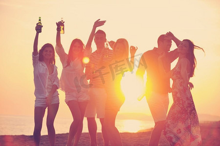 一群年轻人在美丽的日落时在海滩上享受夏日派对