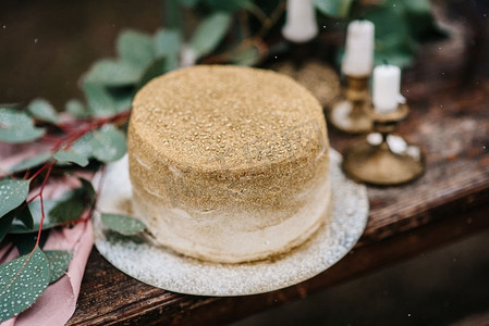 金色婚礼装饰摄影照片_婚礼装饰，在瀑布的背景下，木凳上有一个金色的蛋糕