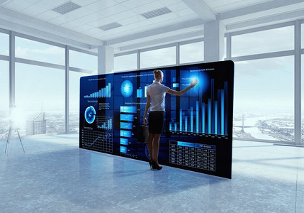 整合新技术。商务女性在办公室使用现代虚拟面板工作的背影