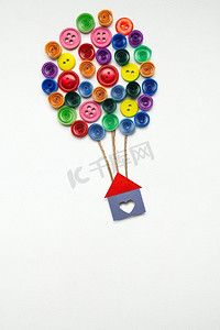 一张创意概念照片，白色背景上有纸制气球的房子。