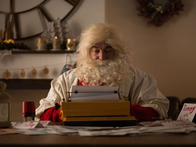 圣诞老人在家工作。在打字机上阅读和书写儿童信件