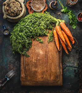 绿色画框摄影照片_质朴的食物背景，切菜板上有一串胡萝卜和绿色蔬菜。俯视图。画框。健康的家庭烹饪。自制菜肴