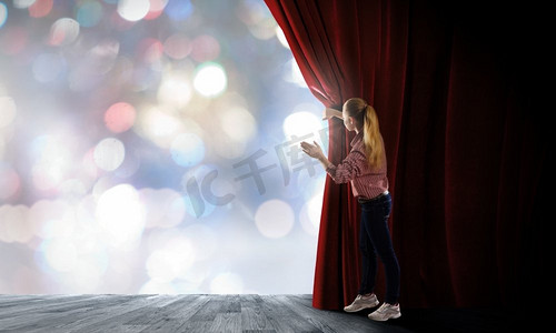 女孩拉开帷幕。穿着休闲开幕舞台窗帘的年轻女子