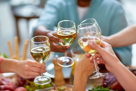 家庭度假摄影照片_庆祝、饮食和度假的概念-手碰酒杯。手握酒杯