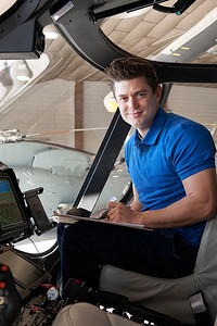 男航空工程师在直升机驾驶舱内用剪贴板工作的肖像