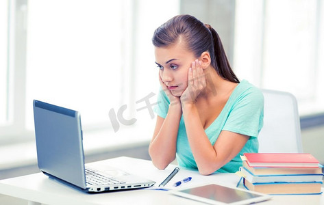 一张压力很大的学生在家里玩电脑的照片。压力很大的学生在家中玩电脑