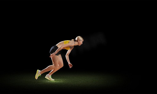 全速前进。年轻女运动员在黑暗背景下跑得很快