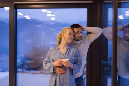 寒冷的冬夜，一对浪漫的年轻夫妇在家中靠窗喝茶
