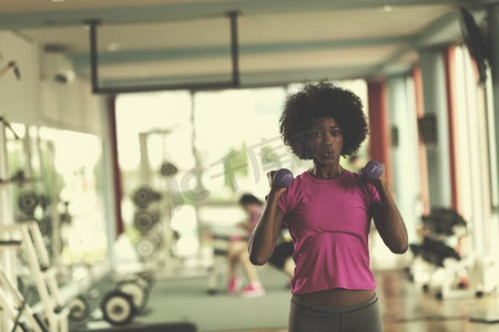 愉快的健康的非洲裔美国妇女在一个crossfit健身房锻炼在重量损失用哑铃.妇女工作出在一个crossfit健身房与哑铃