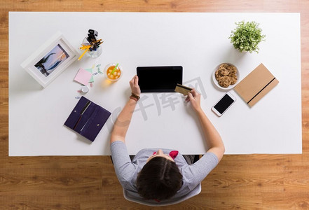 商业、金融和科技概念-餐桌上有平板电脑和信用卡的女人。餐桌上拿着平板电脑和信用卡的女人