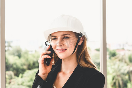 女工程师或建筑师在电话中与团队交谈。