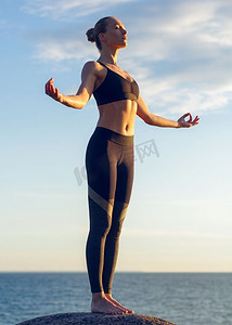 练习瑜伽的高加索健身女性。年轻的高加索健身女子在海边练习瑜伽