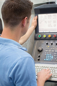 数控切行摄影照片_后视图的男性工程师操作数控机床在工厂