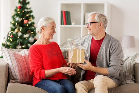 圣诞节、节假日和人们的概念-快乐的微笑着的老夫妇在家中有礼品盒。带着圣诞礼物的快乐微笑的高三夫妇