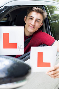 肖像的十几岁男孩通过驾驶考试持有学习板