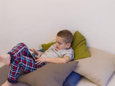 玩电子游戏摄影照片_家里的小男孩在平板电脑上玩电子游戏