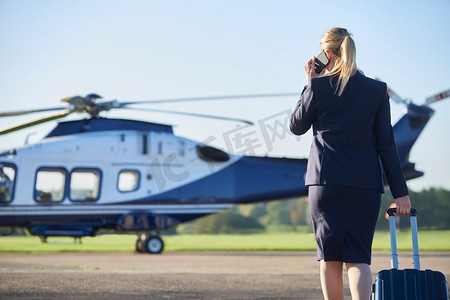 女商人边打手机边走向直升机的背影