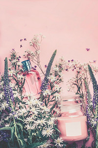 带有草本叶子和花朵的天然化妆品，粉色背景上用于品牌模拟的空白标签，带复制空间的俯视图