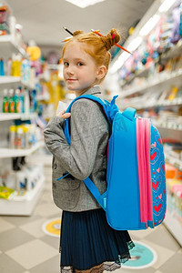 小女生在文具店背包。女童在商店购买办公用品，学生在超市