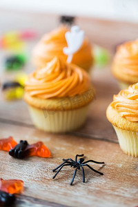 万圣节、派对和节日的概念--蜘蛛装饰，木桌上的糖果和纸杯蛋糕。万圣节派对餐桌上的蜘蛛装饰