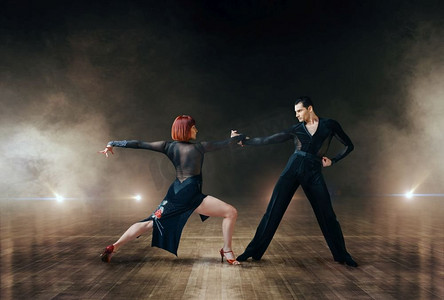 探戈暗色摄影照片_优雅的舞蹈演员在舞台上表演拉丁舞。女性和男性合作伙伴在戏剧现场专业配对舞蹈