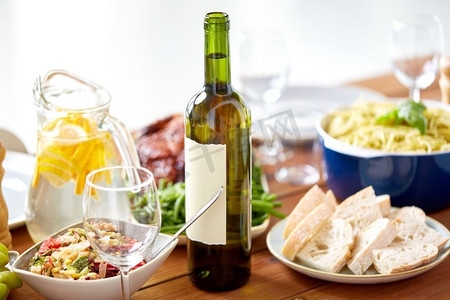 酒精饮料、食物和饮食概念-在上桌的木桌上放一瓶葡萄酒和食物。上桌的木桌上有一瓶葡萄酒和食物