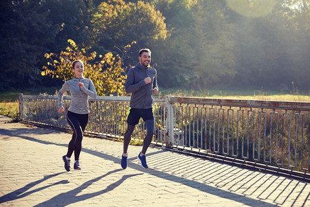 健身，运动，人和慢跑的概念-快乐的情侣在户外跑步。快乐的情侣在户外跑步