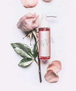 粉红玫瑰精华化妆品瓶，白色背景上有玫瑰花和花瓣，顶视