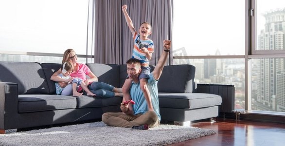 幸福之家。爸爸、妈妈和孩子玩电子游戏爸爸和儿子一起在地板上玩电子游戏
