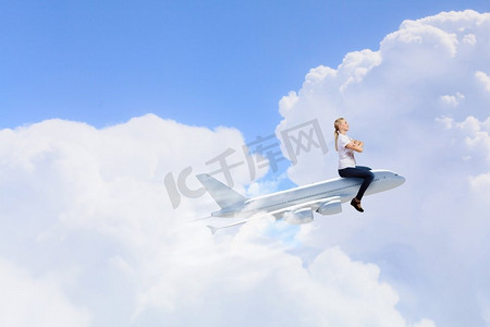 坐飞机摄影照片_一位年轻女子骑着拉着的飞机在空中飞行。女乘客坐飞机
