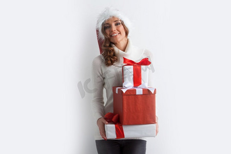 礼物一堆摄影照片_圣诞老人帽子的节日金发妇女拿着堆的圣诞礼物在白色背景。女人拿着一堆礼物